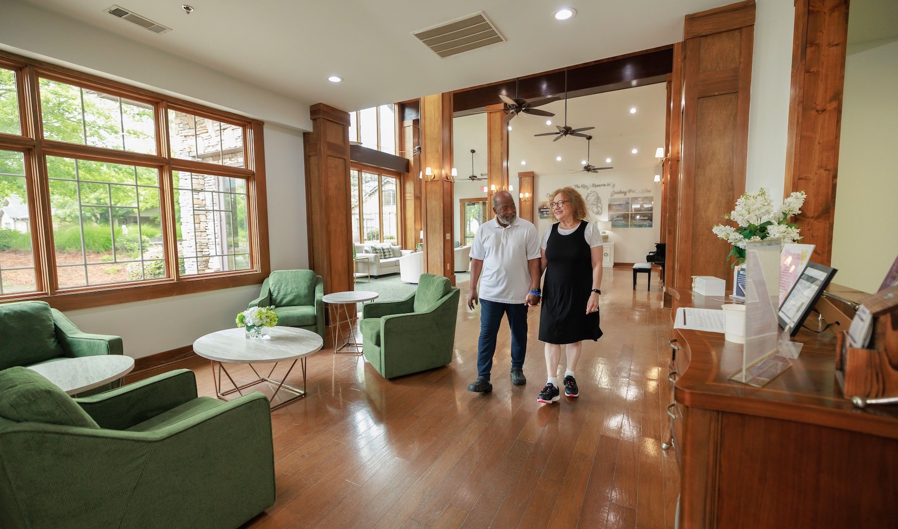 a couple walking through a lounge with seating and windows