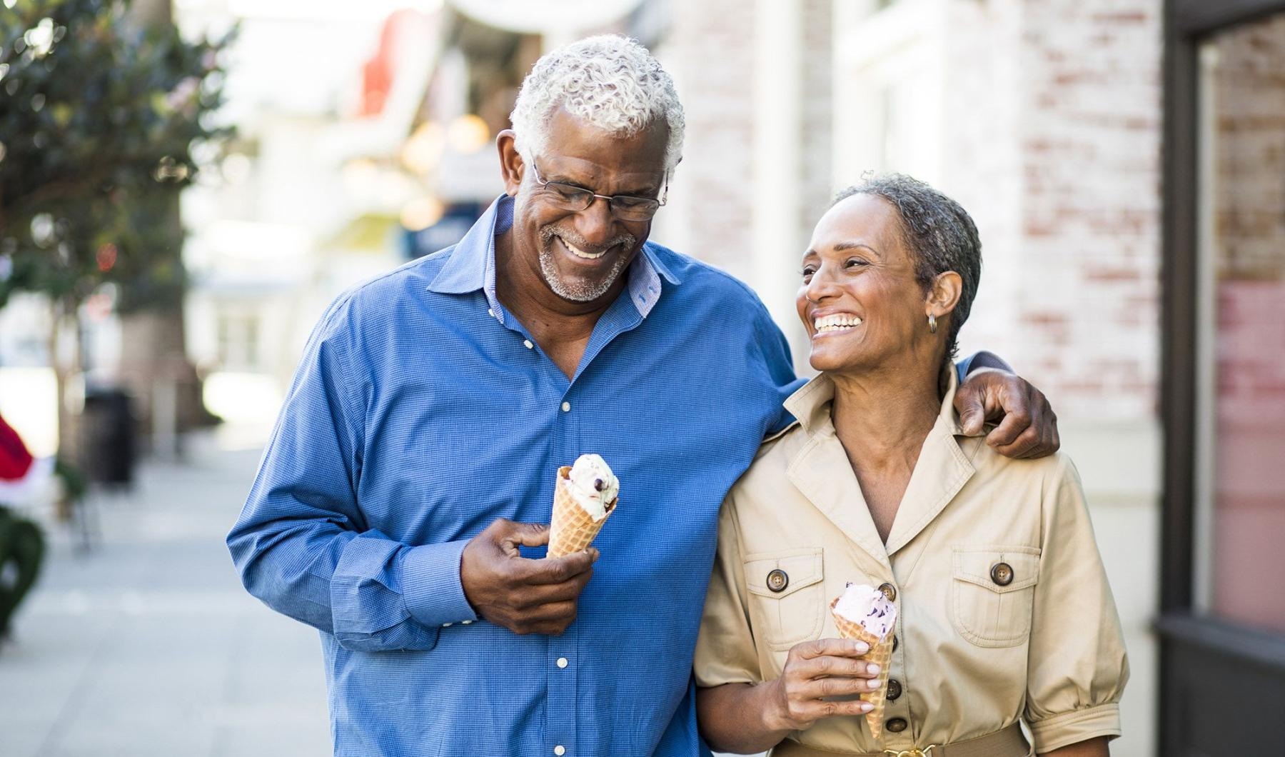Close to the center of everything older couple walks down city sidewalk while holding ice cream cones